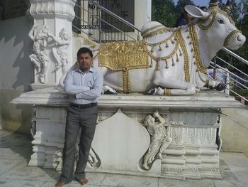 Portrait of man standing against statue