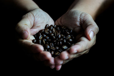 Close-up of hand holding roasted coffee beans