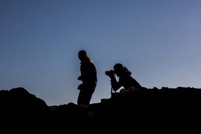 Low angle view of silhouette people against clear sky