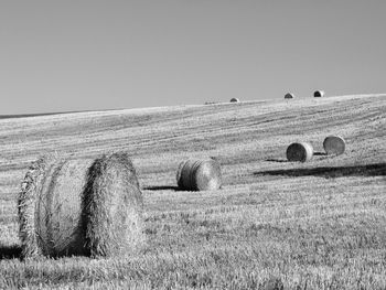 Hay bales on field against clear sky