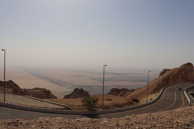 Scenic view of road by mountains against clear sky