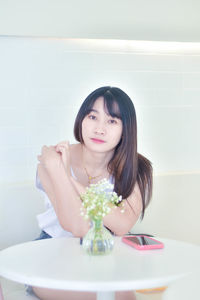 Portrait of smiling young woman sitting on table