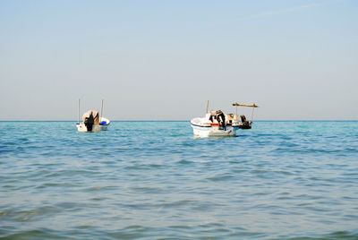 People on boat sailing in sea against clear sky