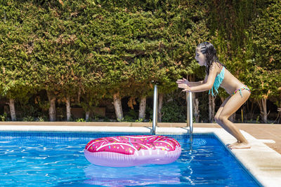 Lttle girl jumping on a rubber ring into a pool