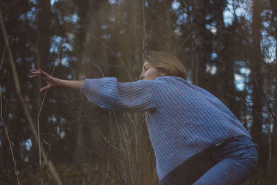 Low section of woman standing by tree in forest