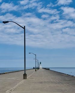 Street light on beach against sky, lighthouse in distance