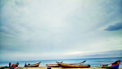 Boats in sea against cloudy sky