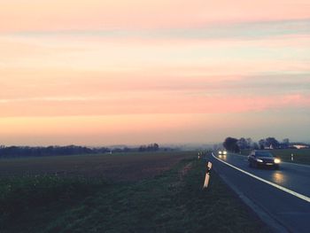 Road on field against sky during sunset