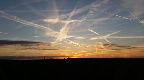 Silhouette vapor trail against sky during sunset