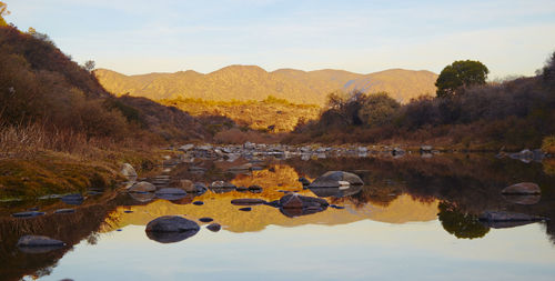 Scenic view of lake by mountains against sky