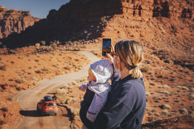 A woman with a child is taking pictures in valley of the gods, utah