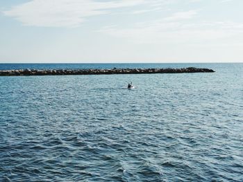 Scenic view of sea against sky. a man is canoeing in the calm sea. 