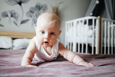 A baby sit on the bed, learning to sit