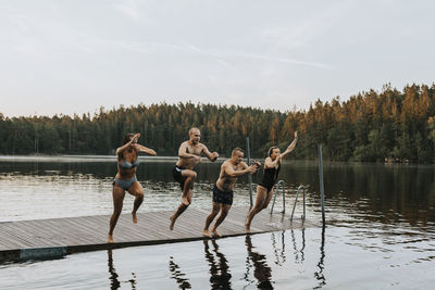 Friends jumping into lake