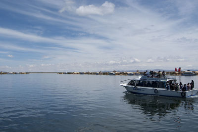 Boats in sea against cloudy sky