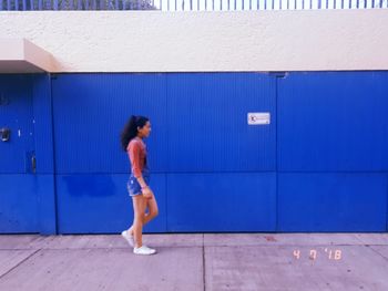 Full length of woman standing against blue wall