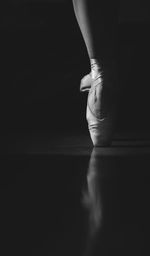 Low section of ballerina balancing on toe against black background