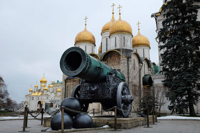 Large canon in front of gold domed cathedral at the kremlin in moscow