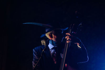 Man playing guitar against black background