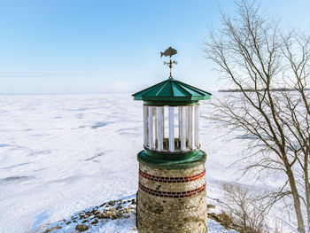 The lake is frozen over with a blue sky but this old landmark still stands watch over the water.