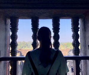 Rear view of woman standing against pillar