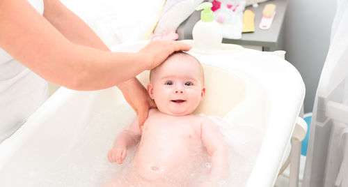 Mother giving bath to baby girl 