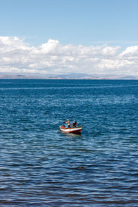 Men on boat in sea against sky