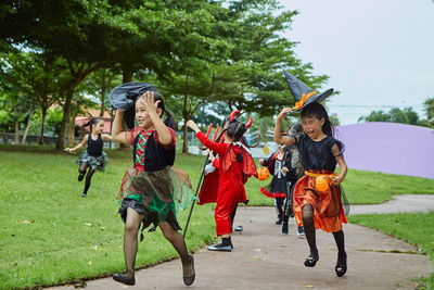 Girls in halloween costumes running on footpath at park