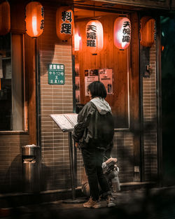 Rear view of man in illuminated building at night