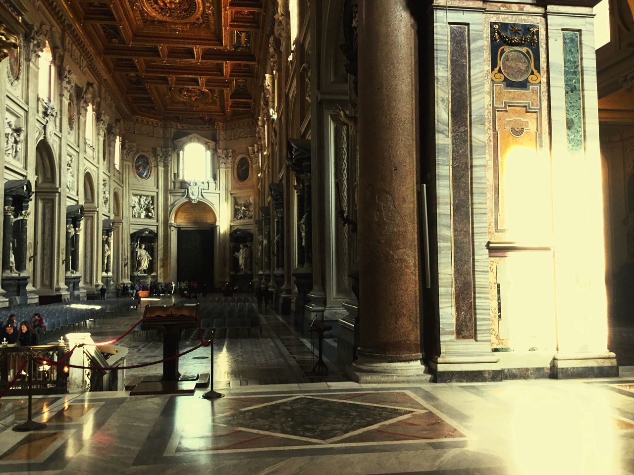 indoors, architecture, built structure, illuminated, flooring, architectural column, interior, arch, corridor, empty, chair, window, lighting equipment, tiled floor, absence, ceiling, incidental people, place of worship, church, architectural feature