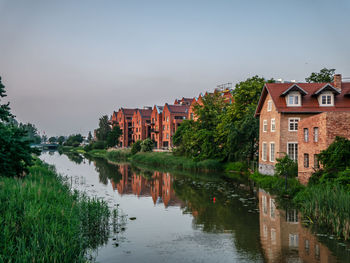 River amidst houses and buildings against sky