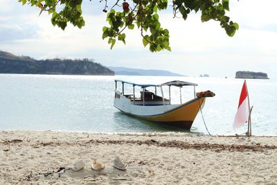 Boat moored on beach against sky