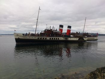 Boats in harbor against cloudy sky