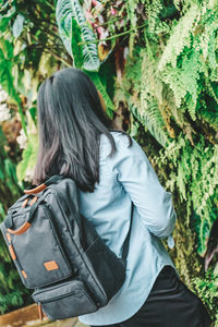 Rear view of woman standing against plants in forest