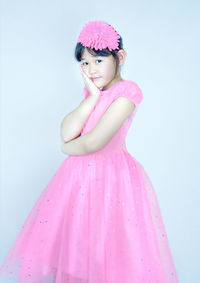 Portrait of woman with pink hair standing against white background