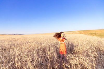 Woman standing on field against clear sky