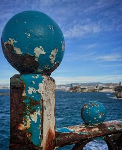 Close-up of coin-operated binoculars by sea against blue sky