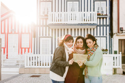 Tourist female friends reading a map in in front of colorful houses.costa nova, aveiro, portugal