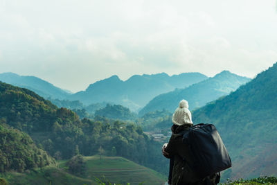 Rear view of man looking at mountain range against sky