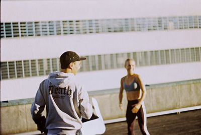 Rear view of women standing against wall
