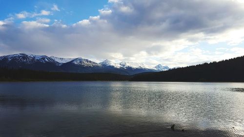 Scenic view of mountains by lake against cloudy sky