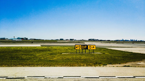 Road sign on field against clear sky