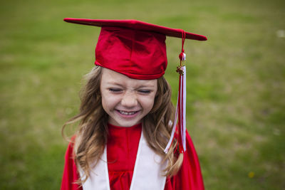 Happy girl in graduation gown on field