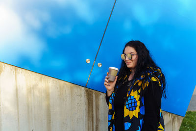 Portrait of young woman standing against wall