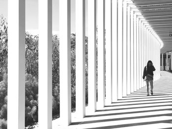 Rear view of woman walking on colonnade