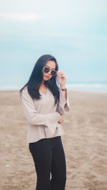 Young woman wearing sunglasses while standing on beach