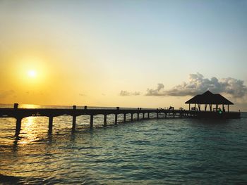 Silhouette pier over sea against sky during sunset