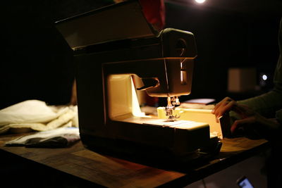 Cropped hand of person touching sewing machine in darkroom