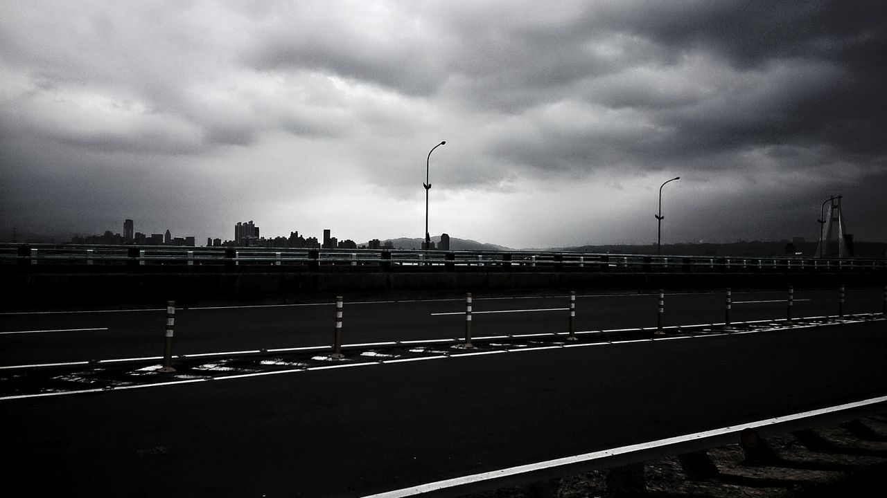 sky, cloud - sky, cloudy, transportation, cloud, overcast, road marking, street light, road, built structure, the way forward, railroad track, weather, dusk, railing, architecture, storm cloud, rail transportation, outdoors, diminishing perspective