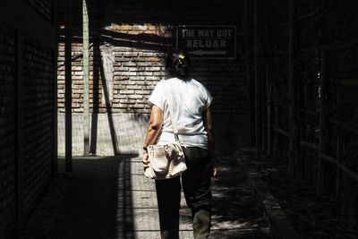 Rear view of man walking on footpath